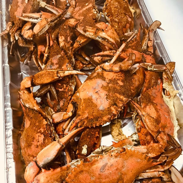 A close-up of a tray filled with steamed blue crabs seasoned with Old Bay.