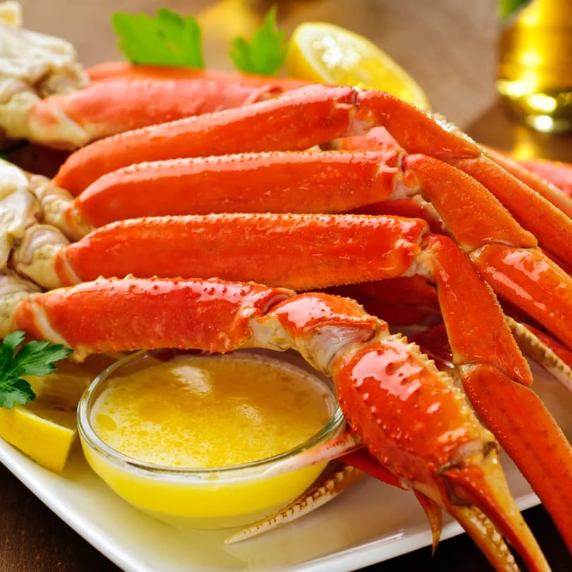 Cameron's Seafood snow crab legs with melted butter, lemon, and parsley on a white plate.