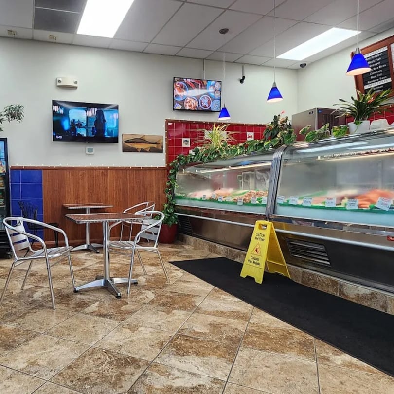 Interior of Cameron's Seafood with display cases of fresh fish, seating, and menu boards.