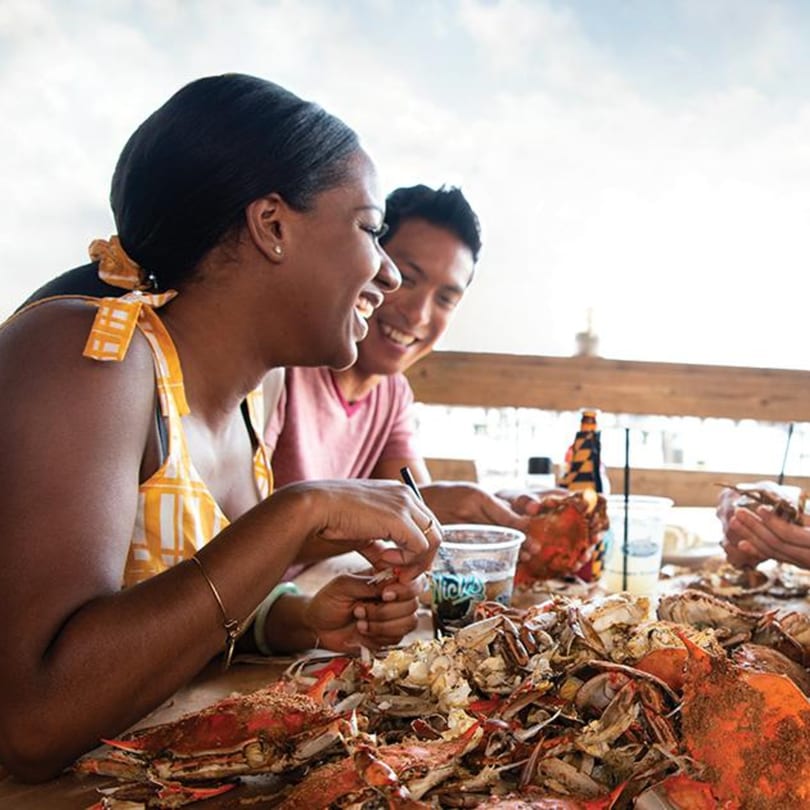 Two people happily eating a large pile of steamed crabs at an outdoor table at Cameron's Seafood.