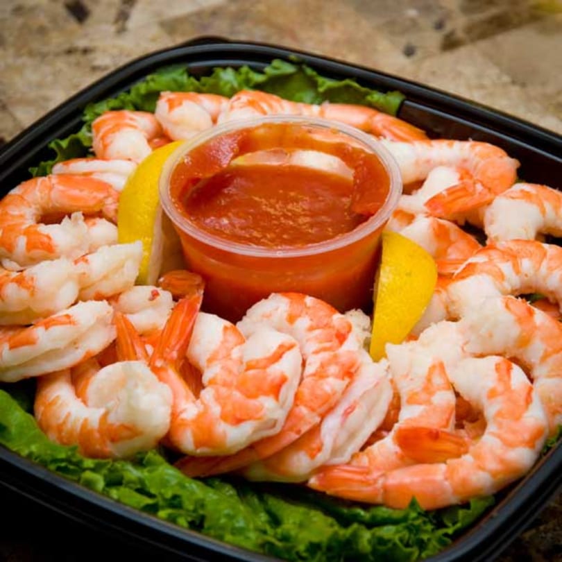 Cameron's Seafood shrimp cocktail with red sauce and lemon wedges on a bed of lettuce.